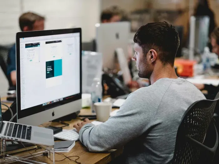 Man working at a desktop computer in a modern office, representing local owners managing listings on our directory